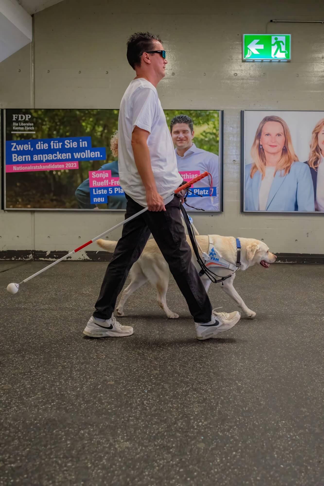 Roger und Layla auf dem beleuchteten Weg einer Unterführung, die zum Bahnhof führt, mit künstlicher Beleuchtung der Passage.